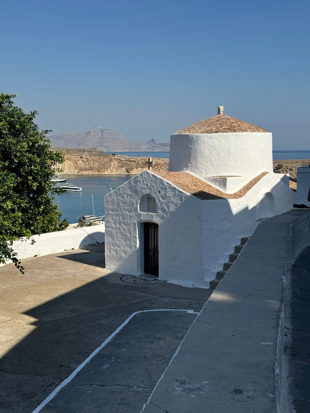 A small whitewashed chapel in Lindos with the harbour and sea beyond