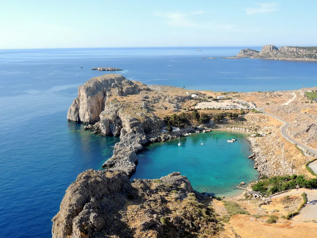 Aerial view of Saint Paul's Bay in Lindos, a near-circular turquoise lagoon enclosed by rock