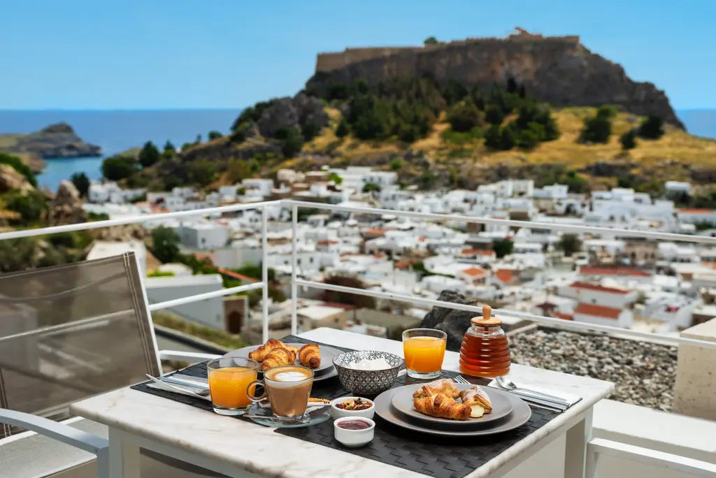 Greek breakfast on a terrace at Lindos Comfy Suites with the Acropolis of Lindos and the village behind
