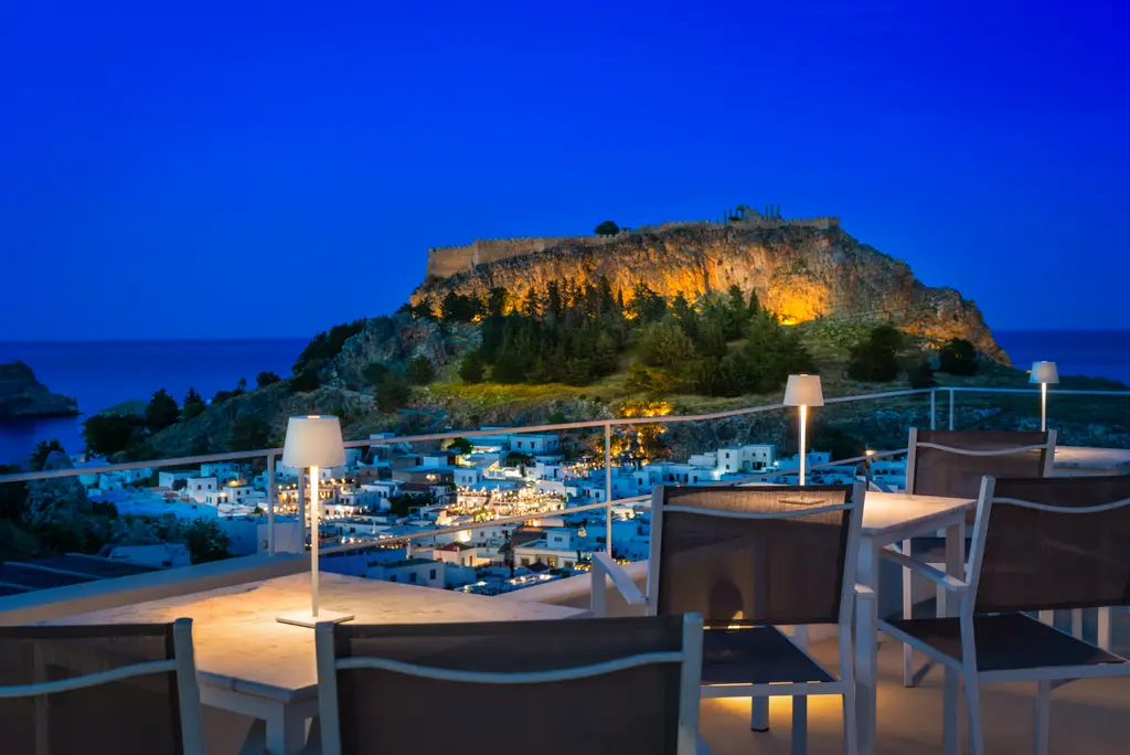 Evening on the terrace at Lindos Comfy Suites with the illuminated Acropolis and village lights